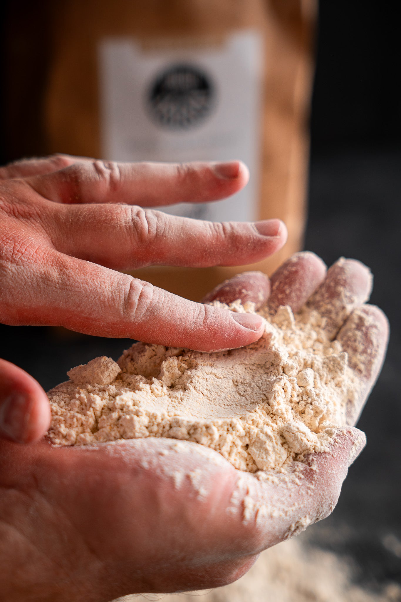 Hands showing the soft, silky texture and golden hue of Proof Flour Mill stone-ground White Sonora flour. Grown in Arizona and the perfect addition to your next pastry.